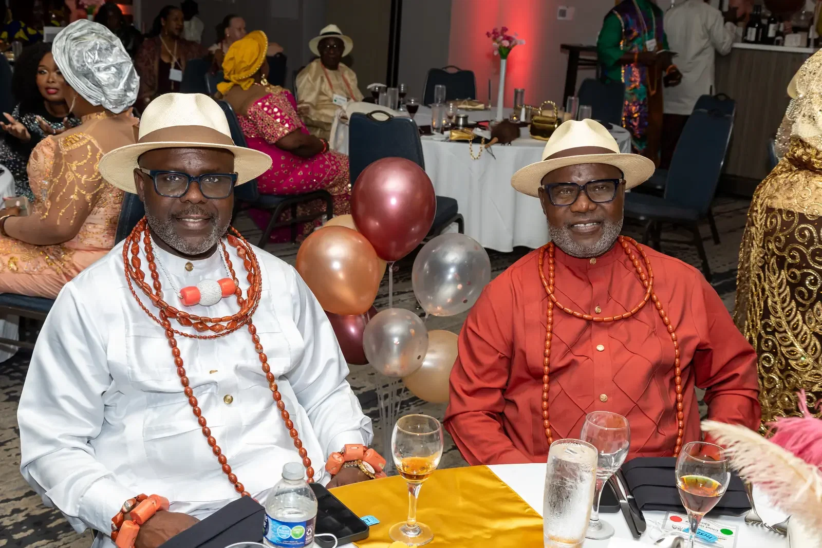 Two elders in coral beads smiling at their table, Gala, Convention 2025, Miami